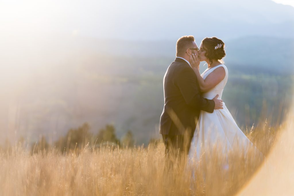Bride and groom kissing in a field.