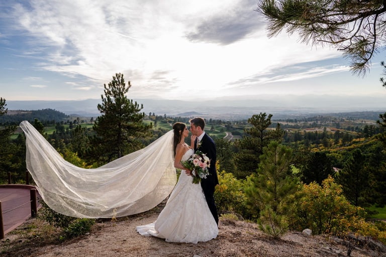 Bride and groom on an overlook with veil blowing in the wind.