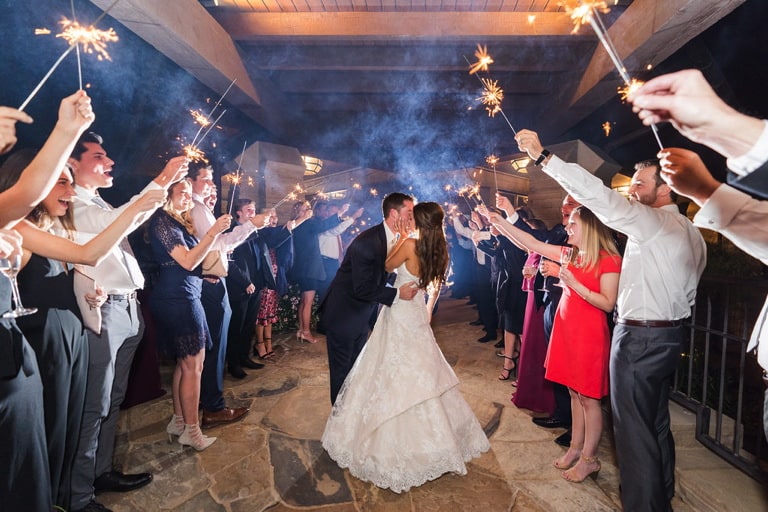Bride and groom kiss during a sparkler sendoff.