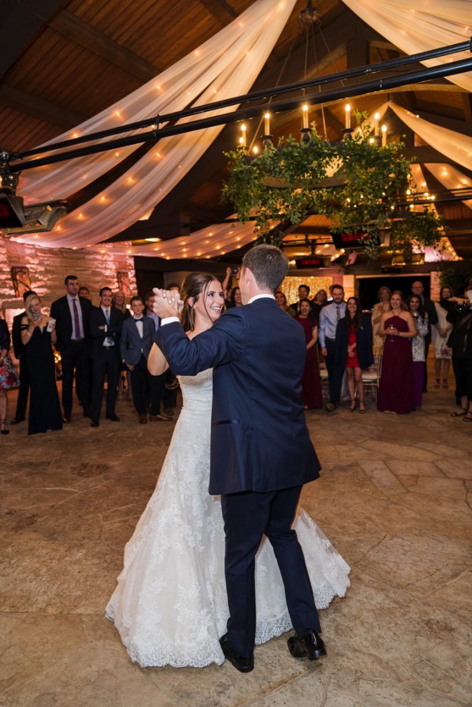 Bride and groom's first dance under twinkle-lit drapery and greenery chandelier.